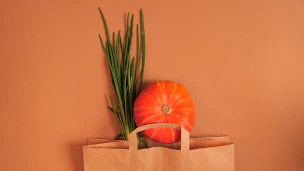 Orange och gröna grönsaker visas i kassen på beige bakgrund. — Stockvideo