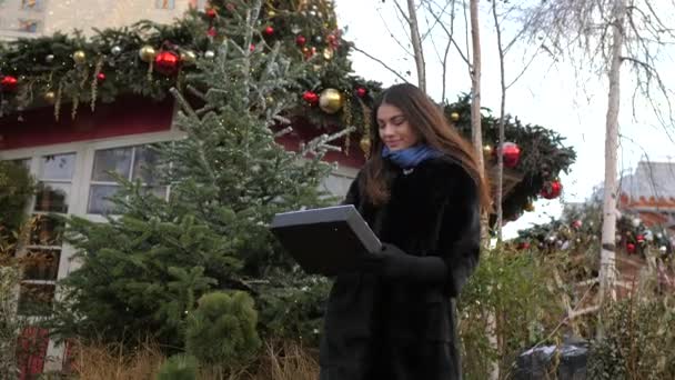 Girl shows sign with inscription happy new year. Festive trees in the background — Stock Video