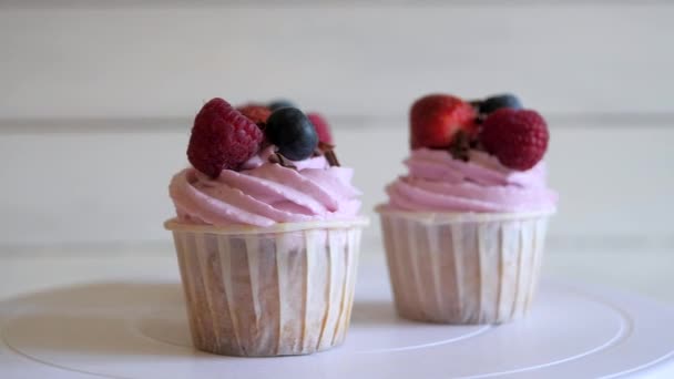 Malinové cupcakes s čerstvými bobulemi otáčet na stojanu na bílém pozadí — Stock video