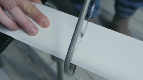 Proces řezání bílých plastových lišt Deska s pilou. — Stock video