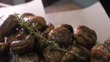 Beyaz el sanatları kağıdının üzerinde otlu ızgara mantarlar var. Sıcak, iştah açıcı yemek döner ve kamera etrafta uçar..