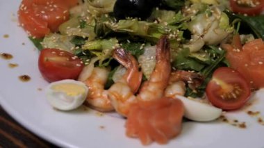 Karides ve zeytinli leziz sezar salatası büyük beyaz bir tabakta döner. Bir restoran için etkileşimli menü ögesi.