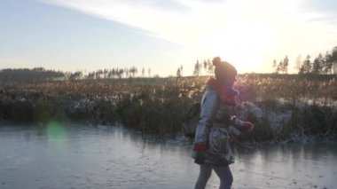 Kız gün batımında donmuş gölde paten kayıyor. Turizm ve kış sporları.