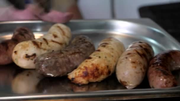 Bavorské smažené klobásy se rozprostírají pomocí speciálních kleští na železném podnose. — Stock video