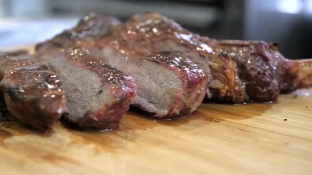 Juicy tamoghawk steak is cut into pieces and lies on a wooden board. — Stock Video