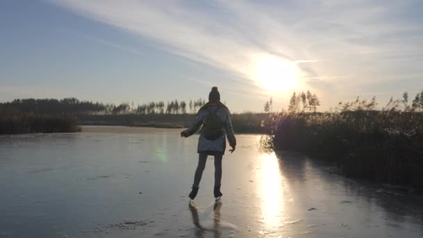 Dívka bruslí na zamrzlém jezeře v paprscích zapadajícího slunce. — Stock video