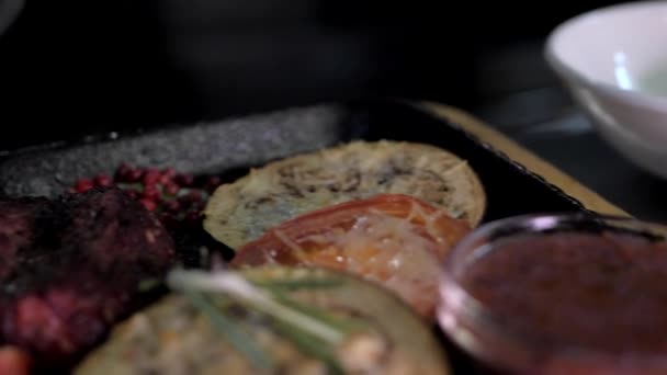 Medium-rare biefstuk met groenten, tomaten en saus op een gietijzeren dienblad — Stockvideo