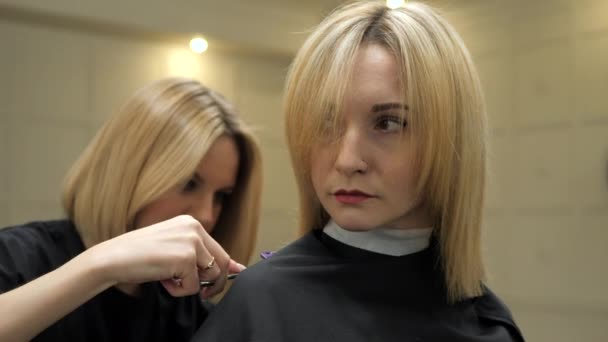 Hairdresser is making haircut to the client woman. Blonde women. — Stok video