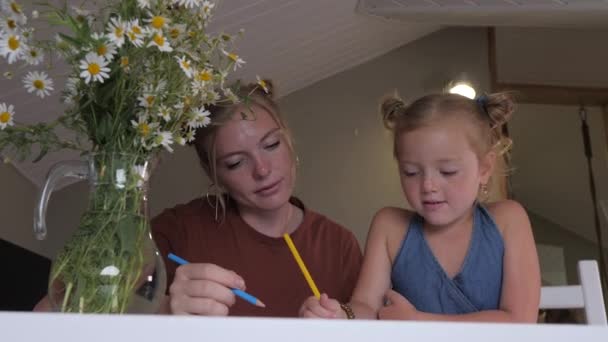 妈妈和女儿正在家里用彩色铅笔一起画画 金发女郎的母亲教她可爱的女儿在餐桌边画画 母亲节 — 图库视频影像