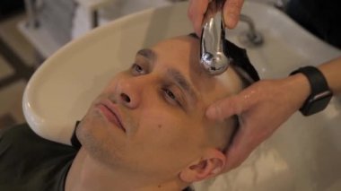 Adam kuaförde saçını yıkarken dinleniyor. Görüntüyü kapat.