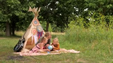 Oynayarak öğreniyorum. Hippi ailesi dışarıda dünyayı kullanarak coğrafya okuyor. Kavram: Annelik 