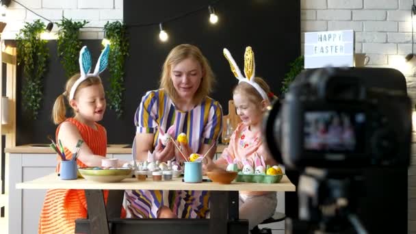 Mamá blogger está decorando huevos de Pascua con sus hijas en casa en interiores — Vídeos de Stock