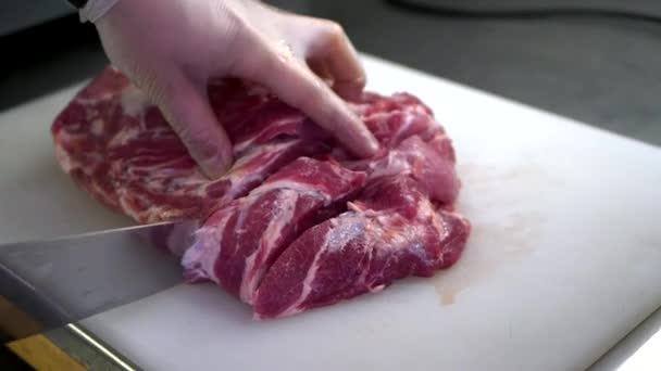 Chef corta carne cruda con el cuchillo en pizarra blanca. — Vídeos de Stock