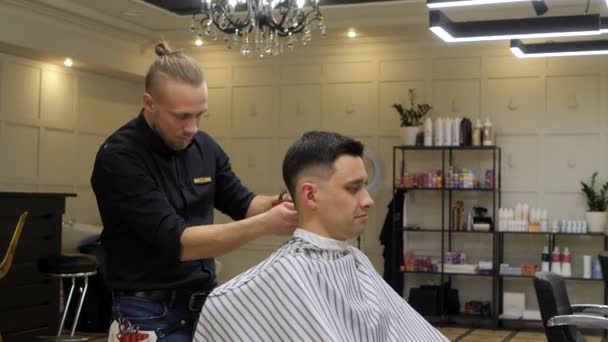 Молодий привабливий чоловік отримує зачіску в перукарні . — стокове відео