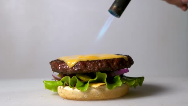 在汉堡包上融化奶酪的过程 用煤气炉把芝士片放在牛肉片上 — 图库视频影像