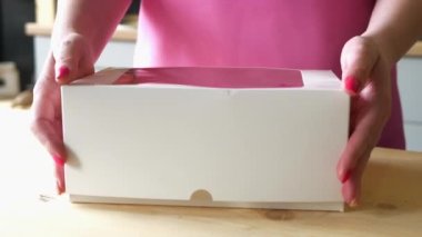 Şekerci, üstünde gül tomurcukları olan parlak pembe fuşya çörekleriyle teslimat kutusunu açar. Doğum günü veya parti konsepti için tatlı teslimatı.