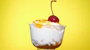Kokteyl kirazlı lezzetli kremalı tatlı sarı arka planda dönüyor. Lezzetli yemek, aldatmaca yemek konsepti