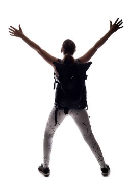 Beyaz bir arka planda yürüyüş yapan ve sırt çantası takan bir kadın modelin arka ışıklandırılmış silueti. Resim kopyalama alanına sahip ve arkaplan eklemek için bileşik kesimler için izole edilmiş