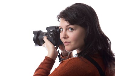 Kadın fotoğrafçının beyaz bir arkaplanda izole edilmiş bir kamera tutarken yan görüntüsü. Model bir dekor veya kopyalama alanı ile yüzleşmek için poz verir