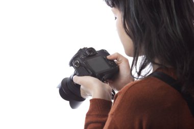 Kadın fotoğrafçının beyaz bir arkaplanda izole edilmiş bir kamera tutarken yan görüntüsü. Model bir dekor veya kopyalama alanı ile yüzleşmek için poz verir