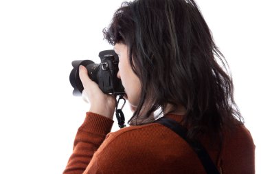 Kadın fotoğrafçının beyaz bir arkaplanda izole edilmiş bir kamera tutarken yan görüntüsü. Model bir dekor veya kopyalama alanı ile yüzleşmek için poz verir