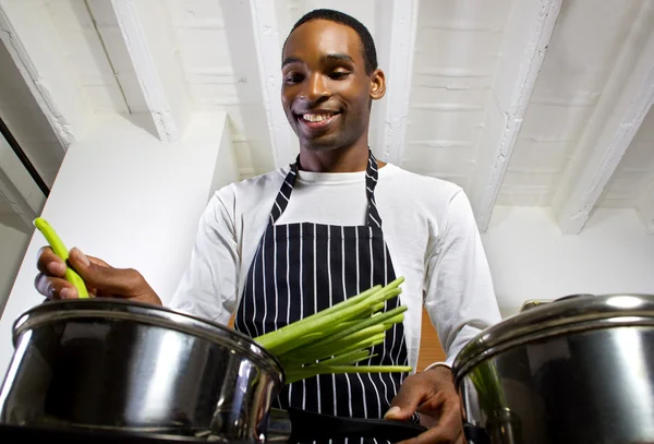 man wearing an apron and cooking at home