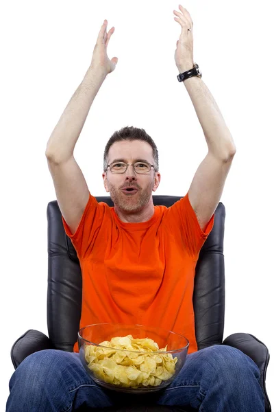 Человек смотрит телевизор и ест чипсы — стоковое фото