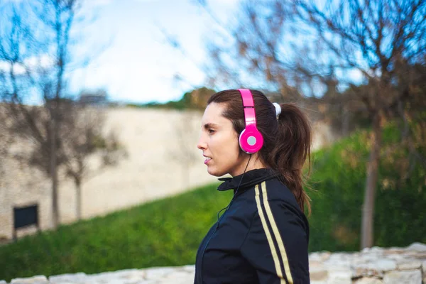 Πορτρέτο μιας αθλητικής νεαρής γυναίκας με ακουστικά κατά την άσκηση σε εξωτερικούς χώρους. — Φωτογραφία Αρχείου