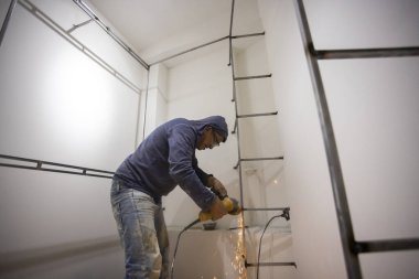 Kolombiyalı metal marangoz soyunma odasında metal parlatıyor.