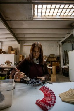 İspanyol kadın bir el fan tasarım atölyesinde çalışıyor.