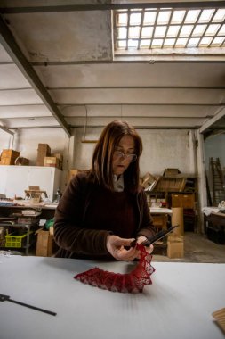 İspanyol kadın bir el fan tasarım atölyesinde çalışıyor.