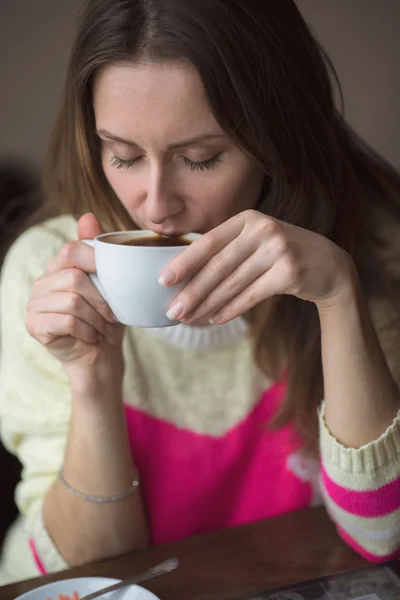 Mladá dívka, sedící v kavárně s šálkem kávy — Stock fotografie