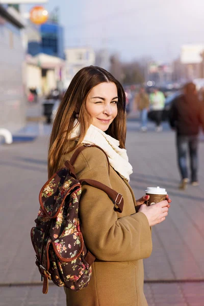 Wanita berambut cokelat cantik memegang tas dan secangkir teh panas atau kopi, berdiri di jalan — Stok Foto