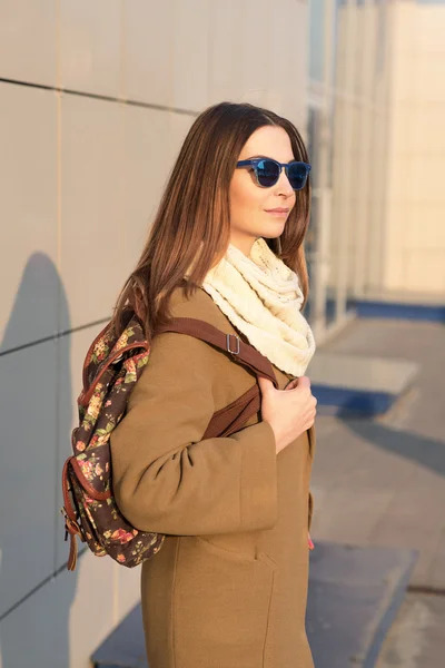 Modemädchen mit Brille und beigem Mantel mit Rucksack-Look — Stockfoto