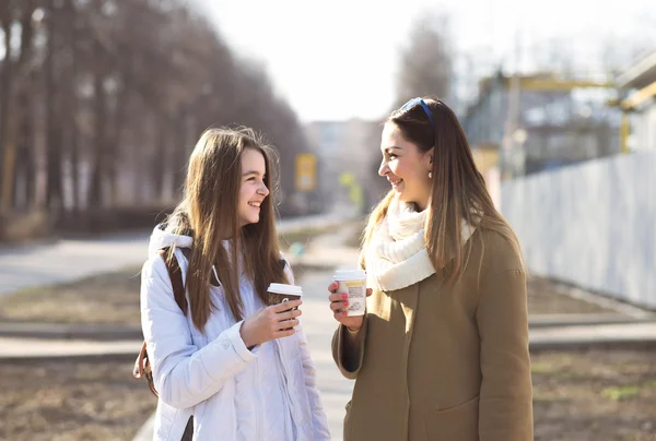 Mother and daughter talking, laughing smiling on the street, drinking coffee in cups Obrazek Stockowy
