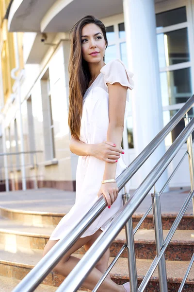 Krásná bruneta stojí na kroky, nákupní centrum, růžové šaty — Stock fotografie