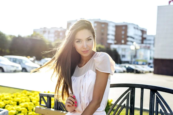 Beautiful girl sitting on a bench, sunny summer day, fashion style urban life — Stock fotografie