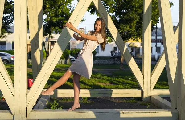 Feliz vestido de mujer morena relajante diversión apoyada en pilas de madera parque disfrutar de sus vacaciones, estilo de moda vida urbana . — Foto de Stock