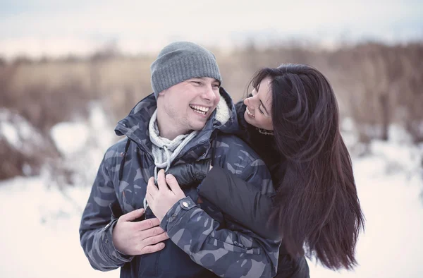 Beautiful young couple hugging and smiling in winter park. Happy family — Stock Photo, Image