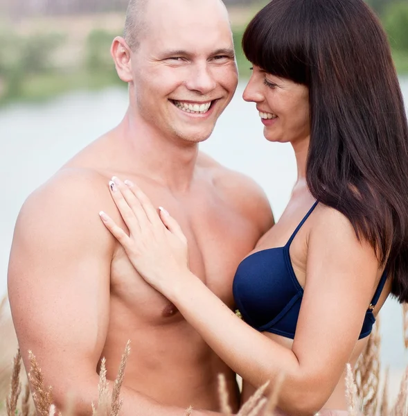 Glückliches Paar lächelt Sommer in Feld auf einem Hintergrund des Sees — Stockfoto