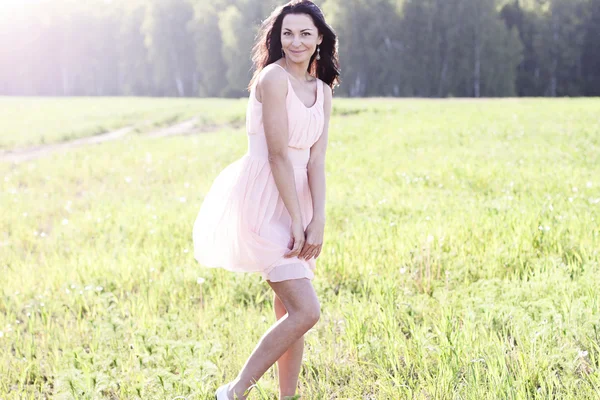 Gyönyörű nő állt egy mező rózsaszín ruha, divat stílus, kültéri álló fogalma — Stock Fotó