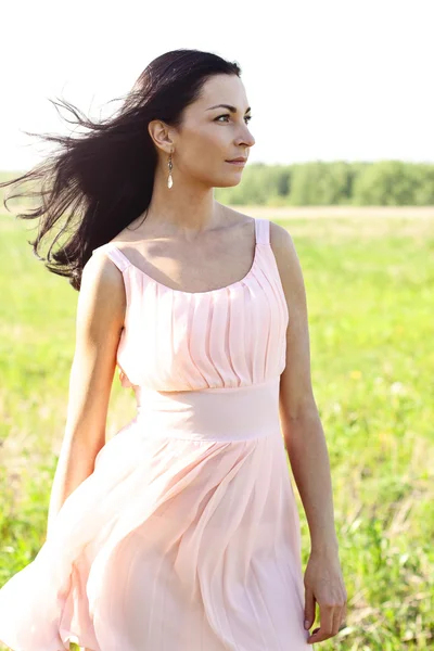 Красивая женщина стоит в поле розовое платье, стиль моды, концепция портрета на открытом воздухе — стоковое фото
