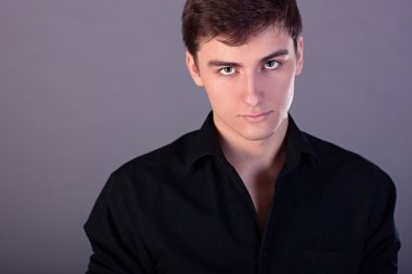 Genç işadamı bir siyah gömlek, moda stil, gençlik yön, kavram fikir iş adam gri arka plan, profesyonel görünüm adam