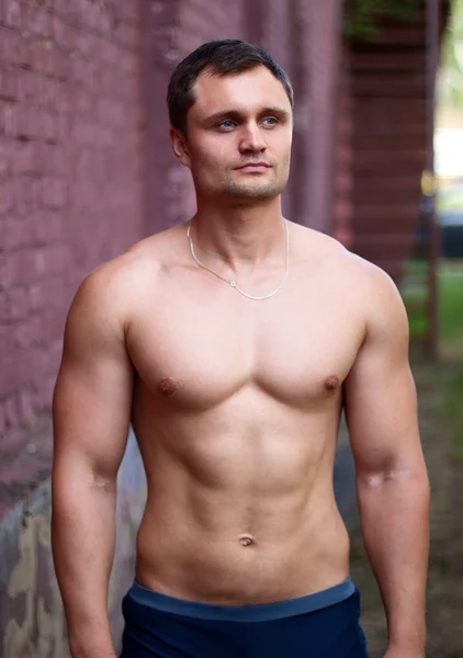 Young man athlete bodybuilder looks into the distance — Stock fotografie