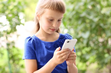 Küçük kız yaz park mavi elbiseli telefonla konuşuyor. Sarışın