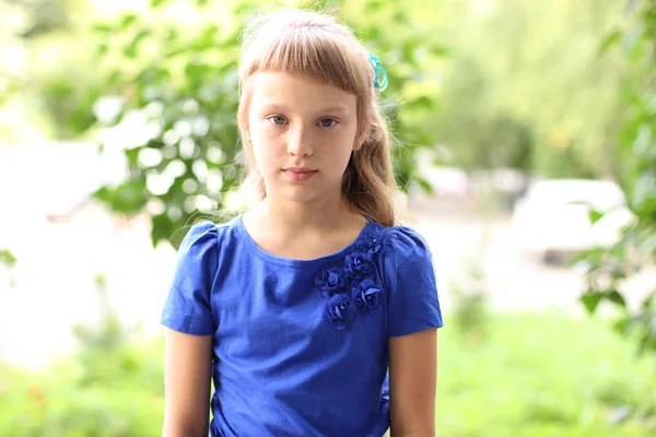 Mała dziewczynka niebieski strój jasny słoneczny dzień parku wśród zielonych krzewów, wyglądający wyobrażenie pojęcia styl moda nastolatek, pozuje do portret — Zdjęcie stockowe