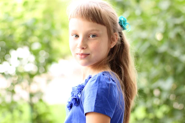 小女孩蓝色穿绿色树丛，看思想理念的青少年的时尚风格，肖像的姿势中的明亮阳光灿烂的夏天天公园 — 图库照片