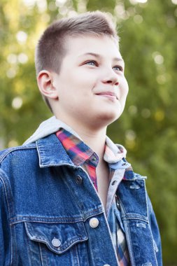 Genç çocuk parkı çayır güneşli bir gün, kot ceket standları, mesafe içine gömlek görünüyor