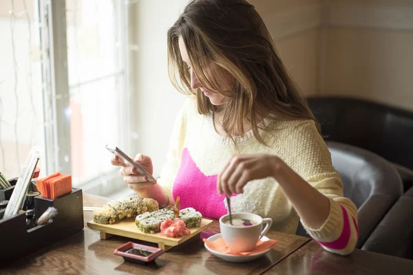 Chica joven, café sentado con taza de café y leer mensajes de teléfono mirando fotos tableta . —  Fotos de Stock