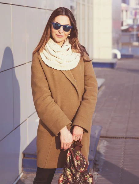 Modní dívka stojící na brýle a béžový kabát s batohem vypadá — Stock fotografie